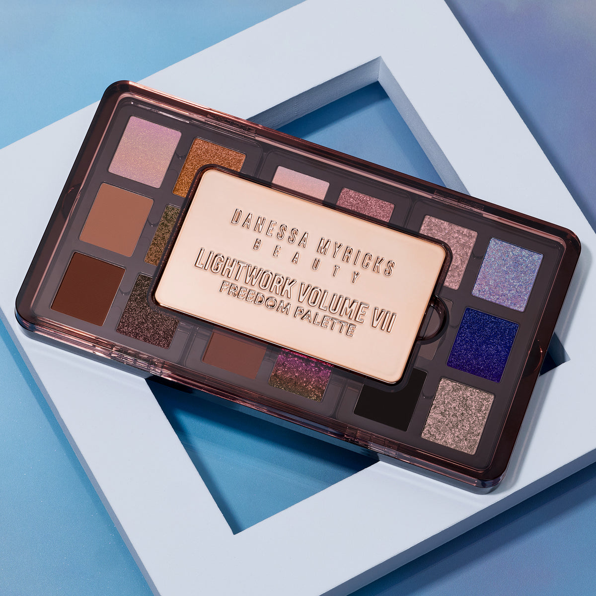 Danessa Myricks Lightwork Volume VII Freedom Palette mit 18 vielseitigen Lidschattenfarben, präsentiert auf einem blauen Hintergrund.