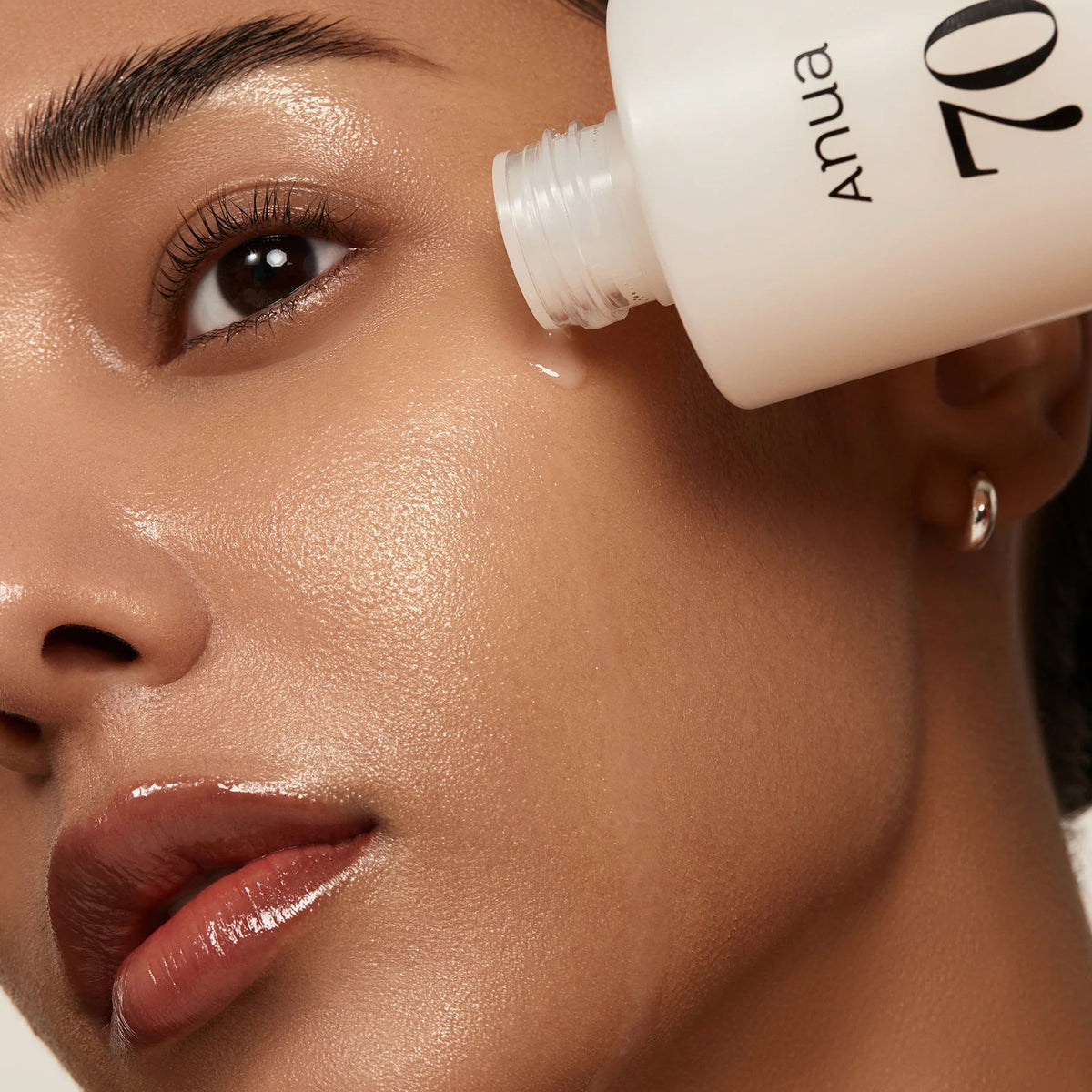 Eine Nahaufnahme einer Frau, die Rice 70 Glow Milky Toner auf ihre strahlende, taufrische Haut aufträgt.