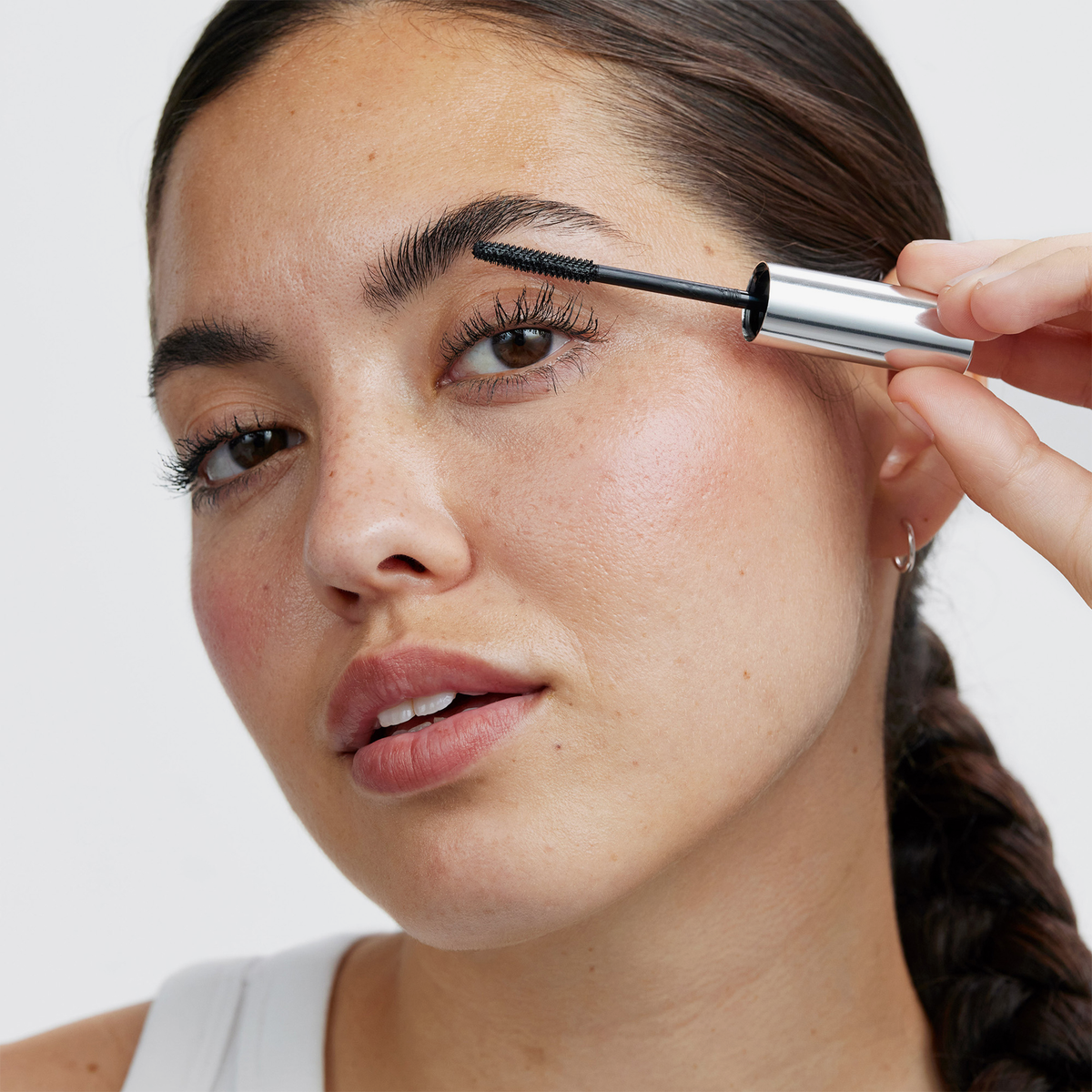 Eine Person, die mit einem Applikator das transparente Lash Booster-Augenbrauengel auf ihre Augenbrauen aufträgt.