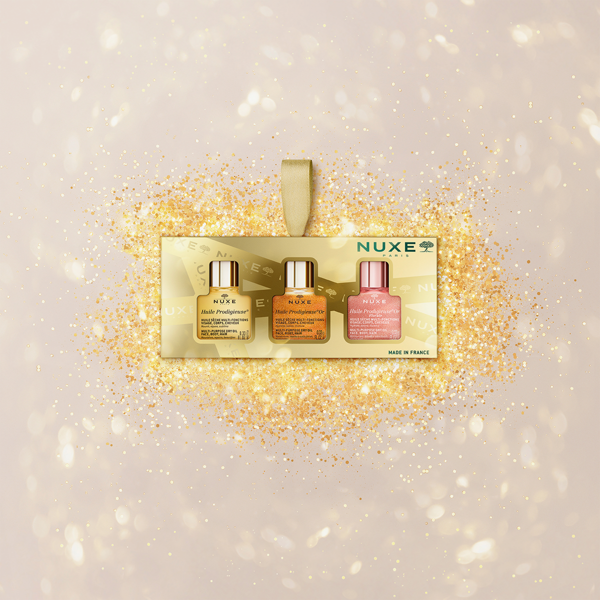 NUXE Geschenkset mit drei Mini-Huile Prodigieuse Ölen in Gold, Rose und Original, vor golden funkelndem Hintergrund inszeniert.