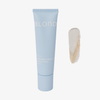 Eine hellblaue BLONDESISTER-Tube mit der Aufschrift „2 IN 1 NATURAL BEAUTY TINTED CREAM SPF15“ neben einem beigen Cremefarbmuster auf weißem Hintergrund.