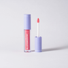 Ein BLONDESISTER 2 IN 1 SWEET GLOSS TINTED LIP OIL mit violettem Verschluss steht neben seinem Applikator mit rosa Gloss.