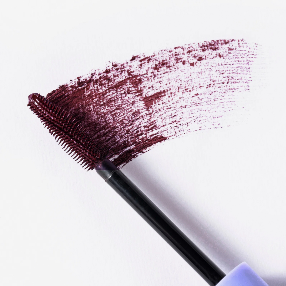 Eine Nahaufnahme der BLONDESISTER 4 IN 1 CLICK & TURN MASCARA in der Farbe „Maroon“, die in einem breiten Strich auf weißem Papier aufgetragen wurde.