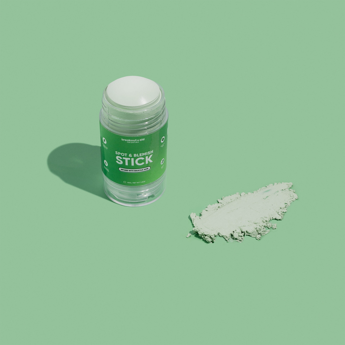 Breakout+aid Blemish & Spot Stick – ein aufdrehbarer Stick zur lokalen Anwendung, neben dem ein Klecks hellgrüner Creme zu sehen ist.