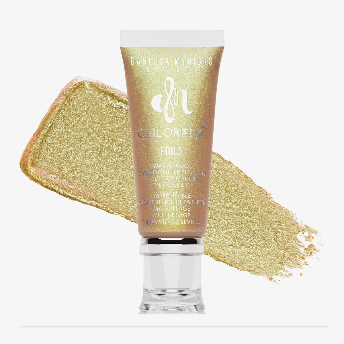 Tube der Danessa Myricks Beauty Colorfix Foils in Jewelz, mit einem Muster des metallischen Goldprodukts dahinter.