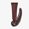 Eine Tube „Danessa Myricks Beauty Glosswork 4D Ultra Shine Plumping Gloss“ mit einem passenden Farbmuster auf weißem Hintergrund.