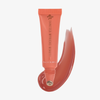 Eine korallenfarbene Tube „Danessa Myricks Beauty Glosswork 4D Ultra Shine Plumping Gloss“ mit einem entsprechenden Farbfleck auf weißem Hintergrund.
