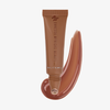 Eine Tube „Danessa Myricks Beauty Glosswork 4D Ultra Shine Plumping Gloss“ mit einem entsprechenden Farbfleck auf weißem Hintergrund.