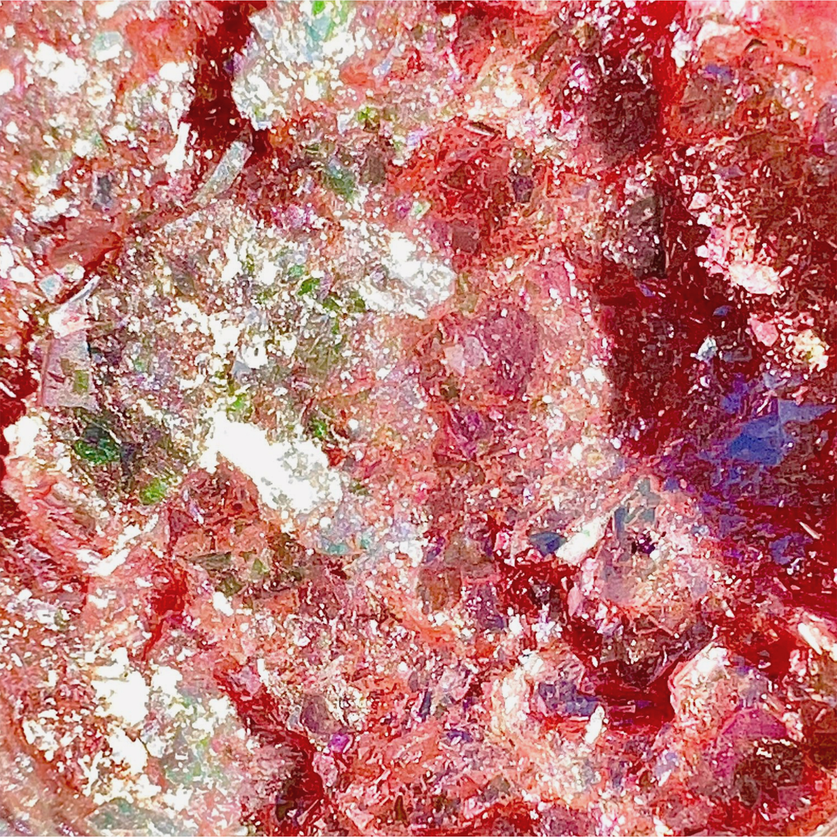 Nahaufnahme von Danessa Myricks Beauty Infinite Chrome Flakes Sweet Tooth in funkelndem Rot und Pink, mit weißen und grünen Reflexen, die eine strukturierte, multidimensionale Oberfläche schaffen.