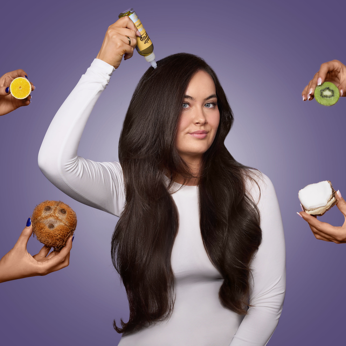 Frau mit langen dunklen Haaren hält eine Flasche "Superfoods" von Hair Syrup an den Kopf; um sie herum Hände mit Superfoods wie Kiwi, Orange und Kokos.