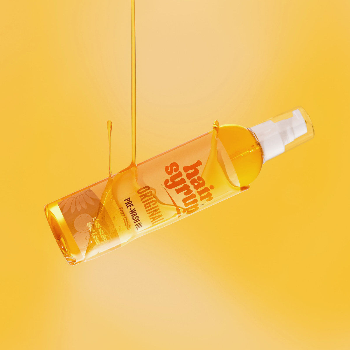 Eine Flasche Hair Syrup's The Original Haaröl, über die eine goldene Flüssigkeit tropft, schwebt vor einem leuchtend gelben Hintergrund.