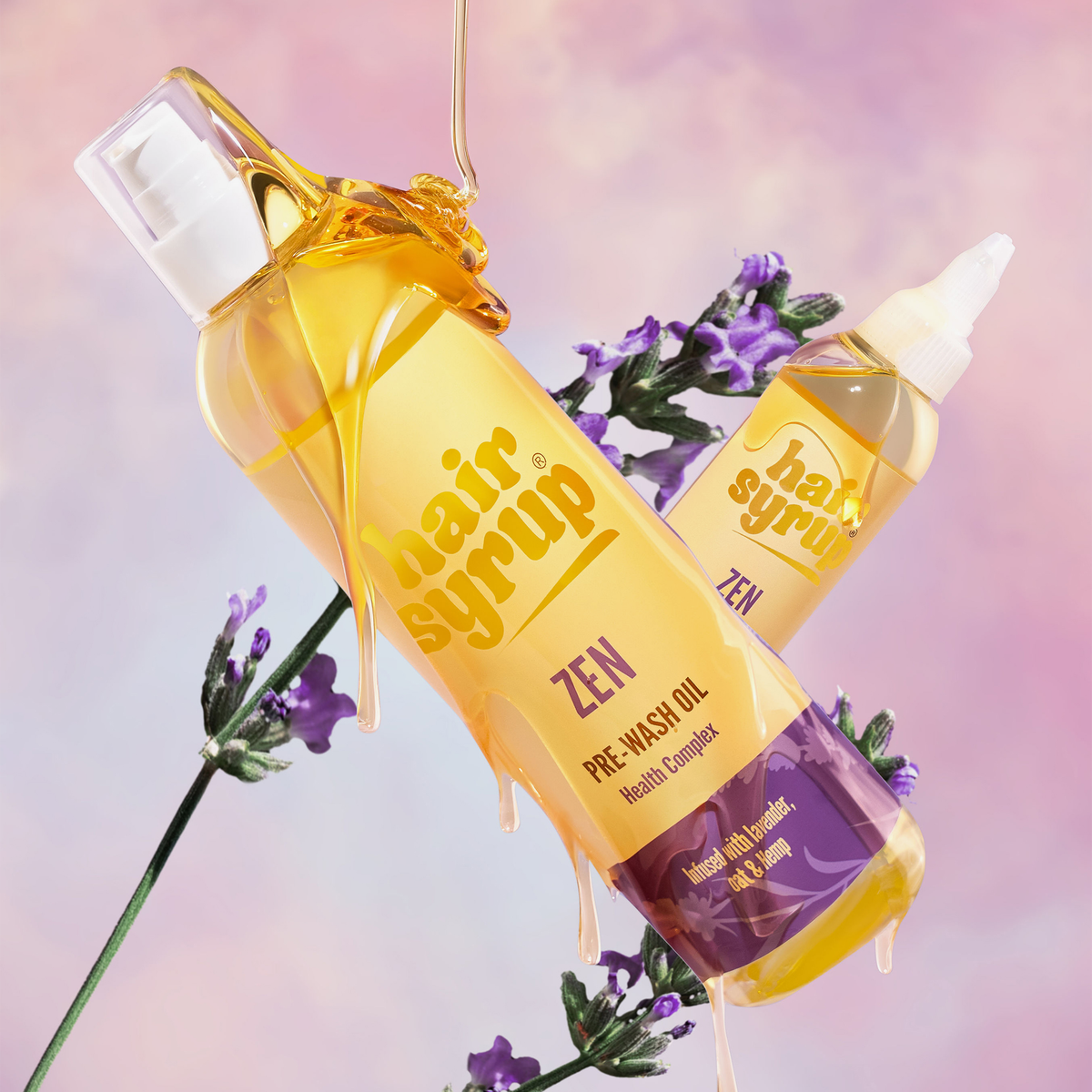Auf einem pastellfarbenen Hintergrund sind zwei Flaschen des Vorwaschöls Hair Syrup Zen mit honigartiger Textur und Lavendelblüten abgebildet.