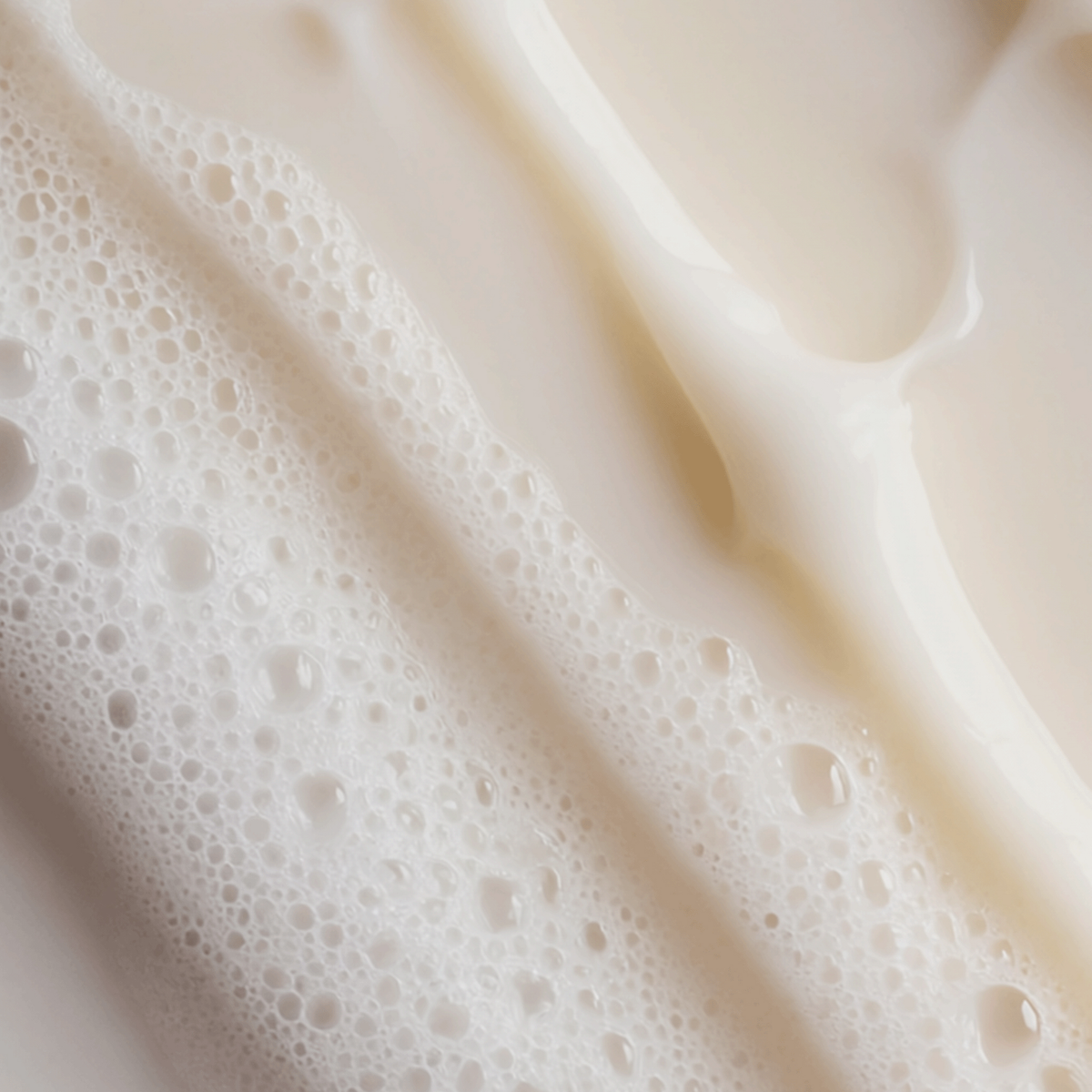 Nahaufnahme von cremigem, weißem Shampoo-Schaum mit feinen Bläschen, der die reichhaltige, schäumende Textur der Formel zeigt
