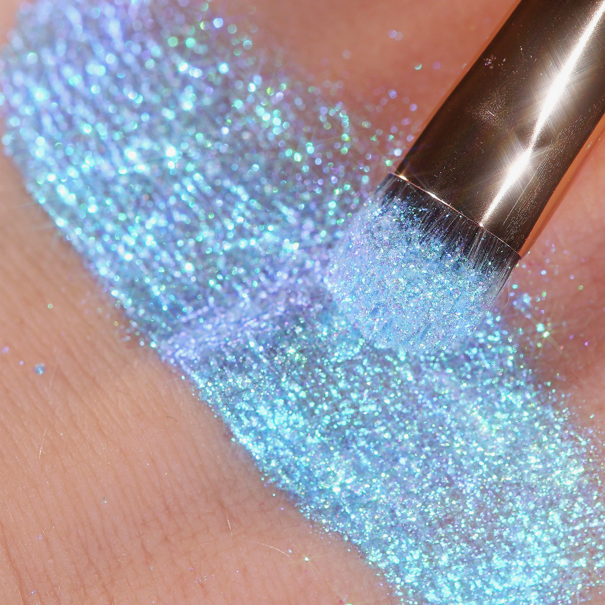 Ein schimmernder, schillernder hellblauer Farbstreifen Opal Multichrome Loose Eyeshadow Dreamer, aufgetragen mit einem Pinsel, auf einem Arm.
