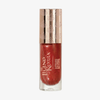 Ein rot schimmerndes Lippenpflegeöl von Lethal Cosmetics, „The Legend of Korra – Embered“, in einem durchsichtigen Fläschchen mit goldenem Verschluss.