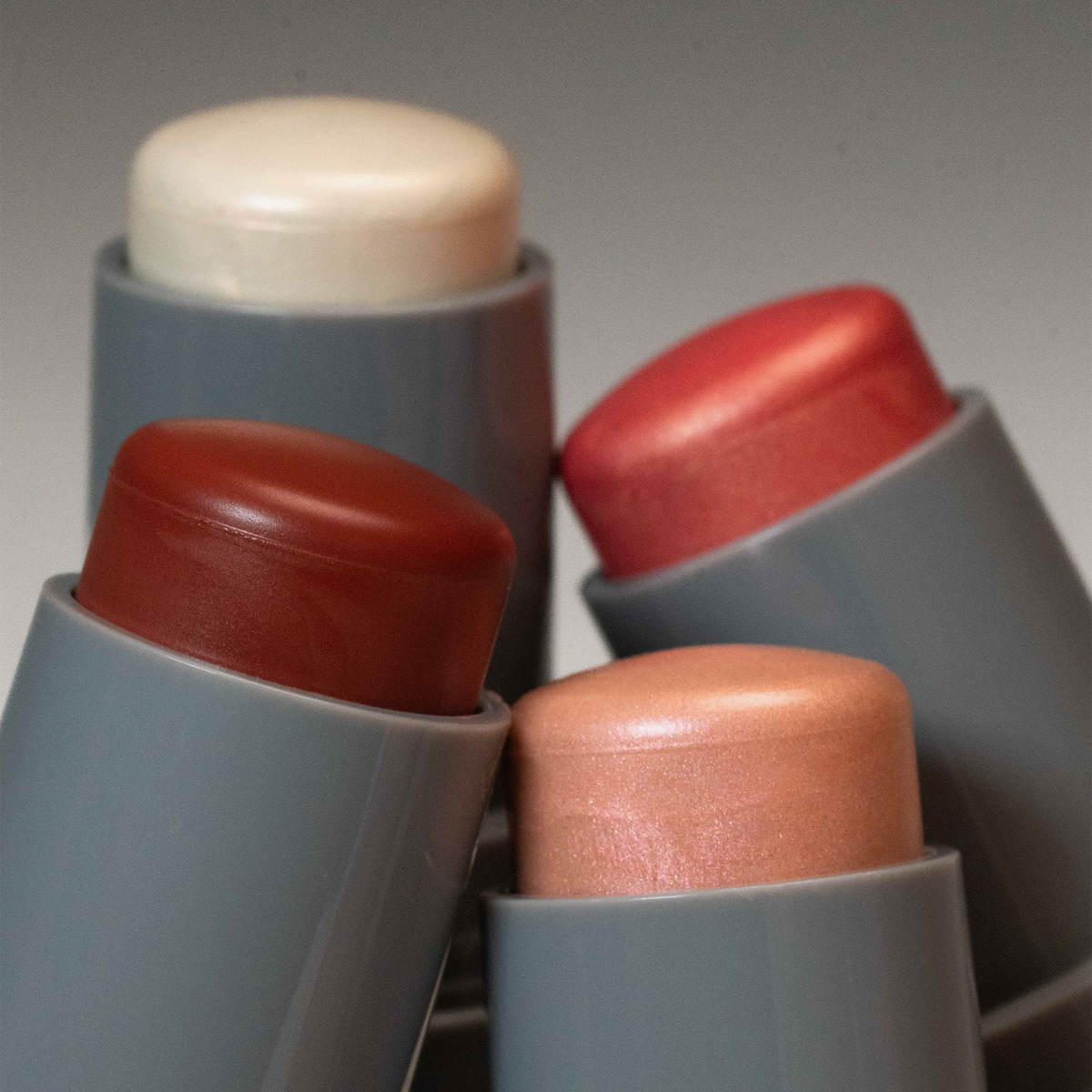 Vier LH Cosmetics Artistick Highlighter - graue Tuben mit weißem, rotem, rosa und pfirsichfarbenem Schimmer.
