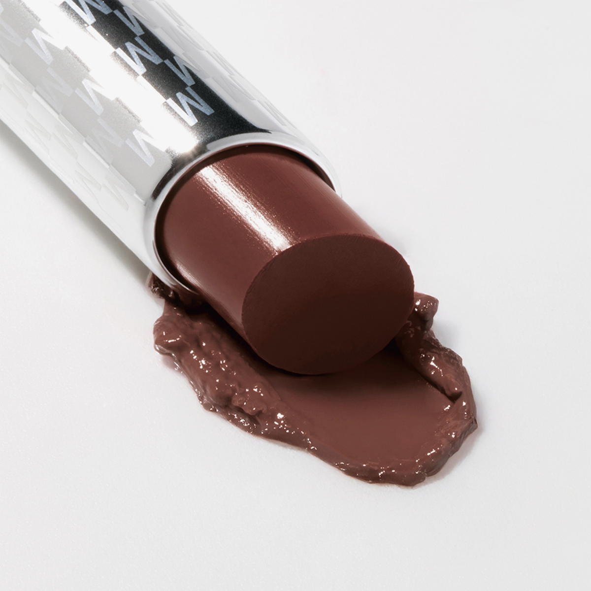 Brauner Lippenstift Mesauda Milano Hydramorphosis, dessen Spitze auf eine weiße Fläche geschmolzen ist.
