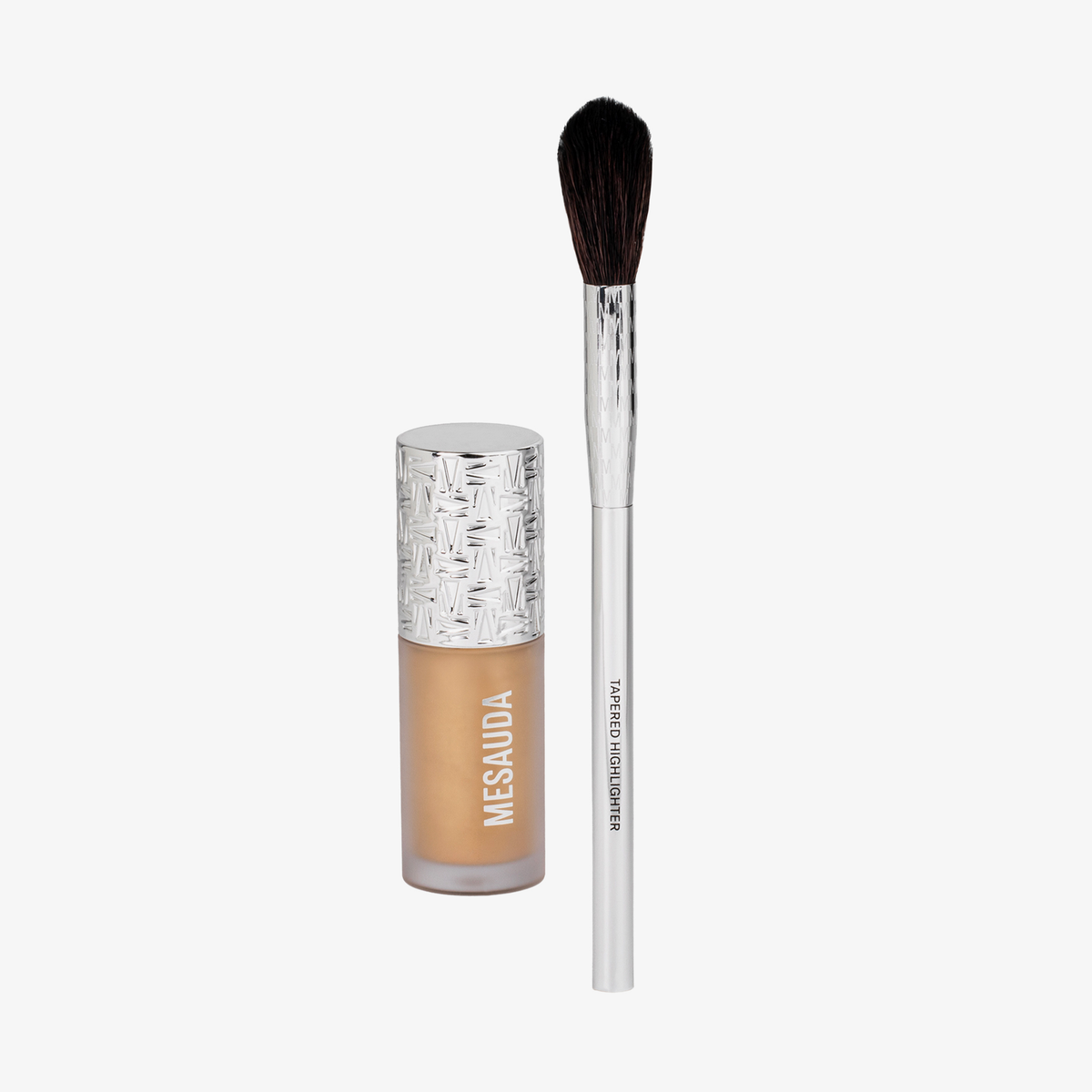 Eine Flasche flüssiger Highlighter und ein spitz zulaufender Make-up-Pinsel aus dem STELLAR GLOW CHRISTMAS KIT.