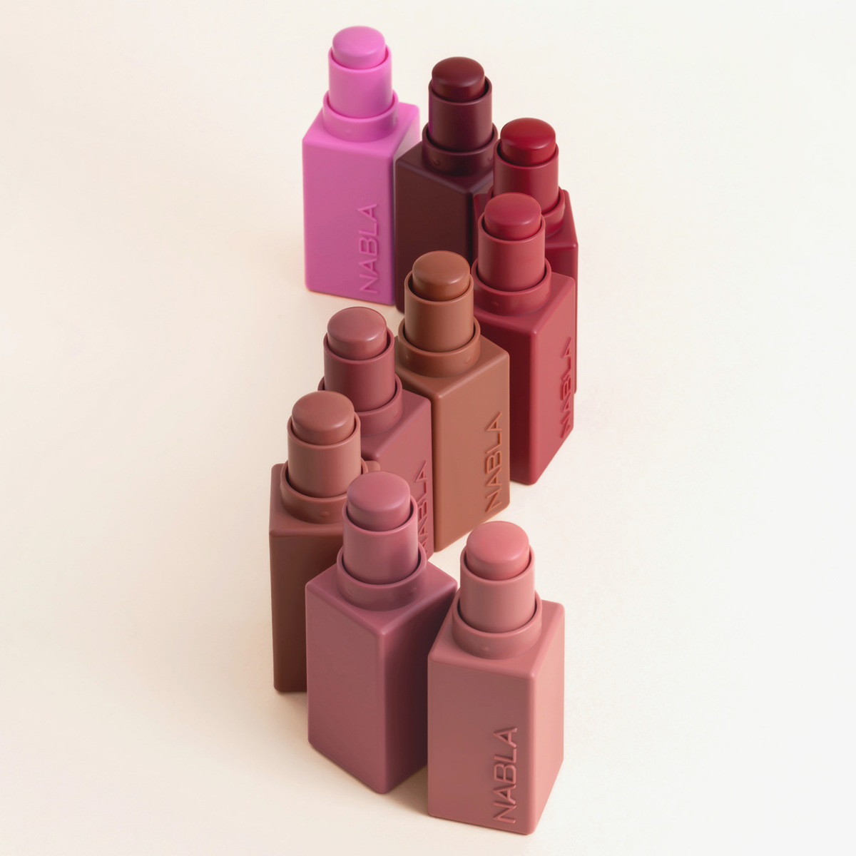 9 „Art Of Skin“-Blush-Sticks von NABLA Cosmetics in Rosa-, Braun- und Rottönen, angeordnet auf einem hellen Hintergrund.