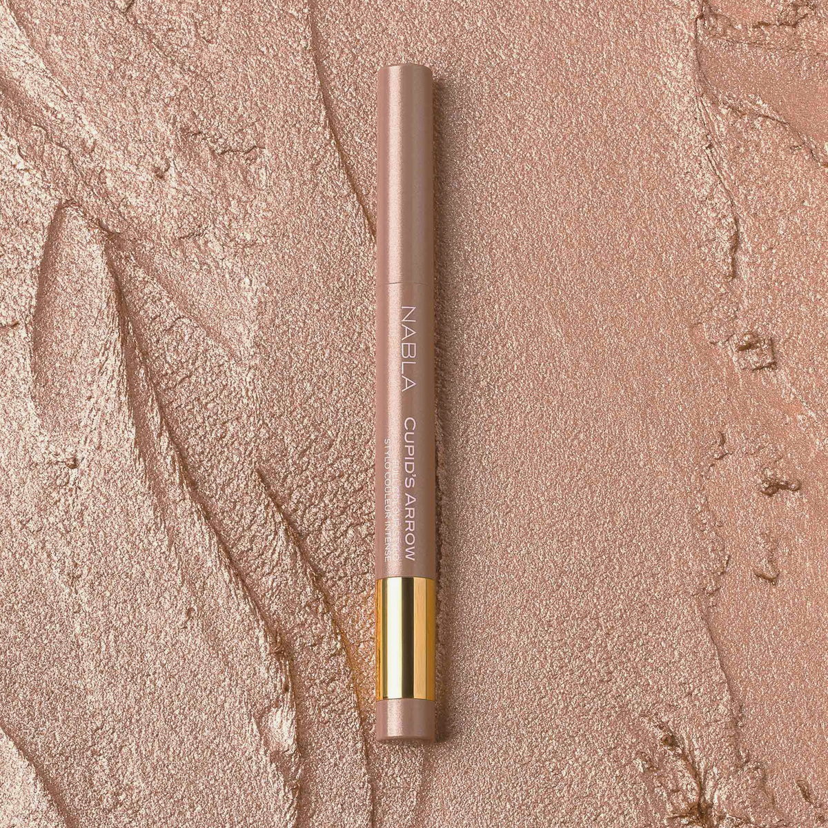 NABLA Cupid’s Arrow Longwear Stylo Arrow Shine in der Nuance Mirror auf schimmernder, strukturierter Oberfläche in warmen Rosé-Gold-Tönen.