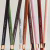 Acht NABLA Cosmetics Cupids Arrow Micro Eye Pencils in verschiedenen Farbtönen sind vertikal auf einem neutralen Hintergrund angeordnet.