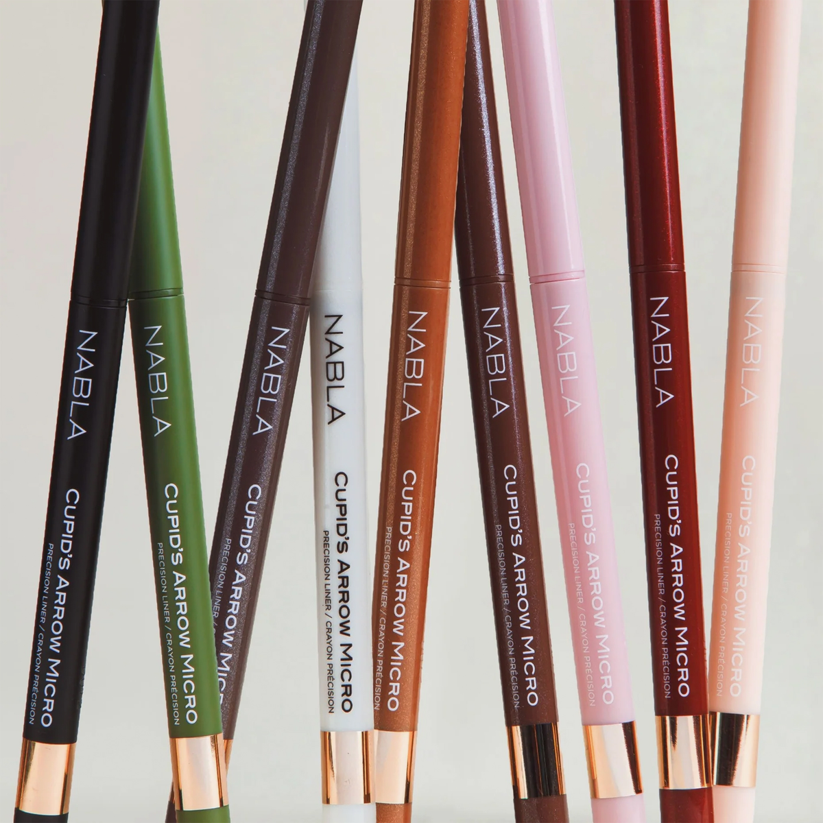 Acht NABLA Cosmetics Cupids Arrow Micro Eye Pencils in verschiedenen Farbtönen sind vertikal auf einem neutralen Hintergrund angeordnet.