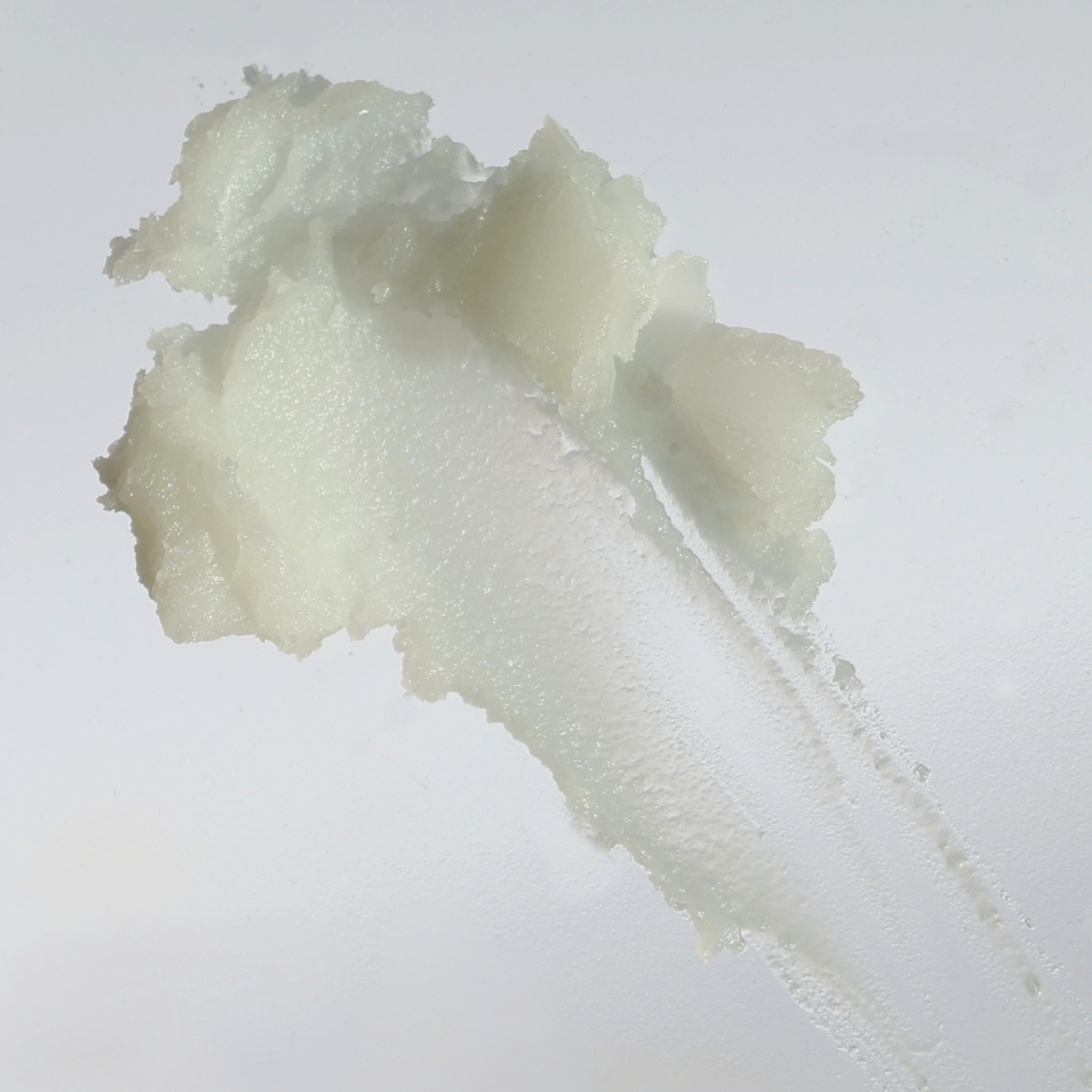 Ein Abstrich von NERDS. Centella-Reinigungsbalsam - eine dicke, weiße, cremige Substanz auf einer glatten, transparenten Oberfläche.