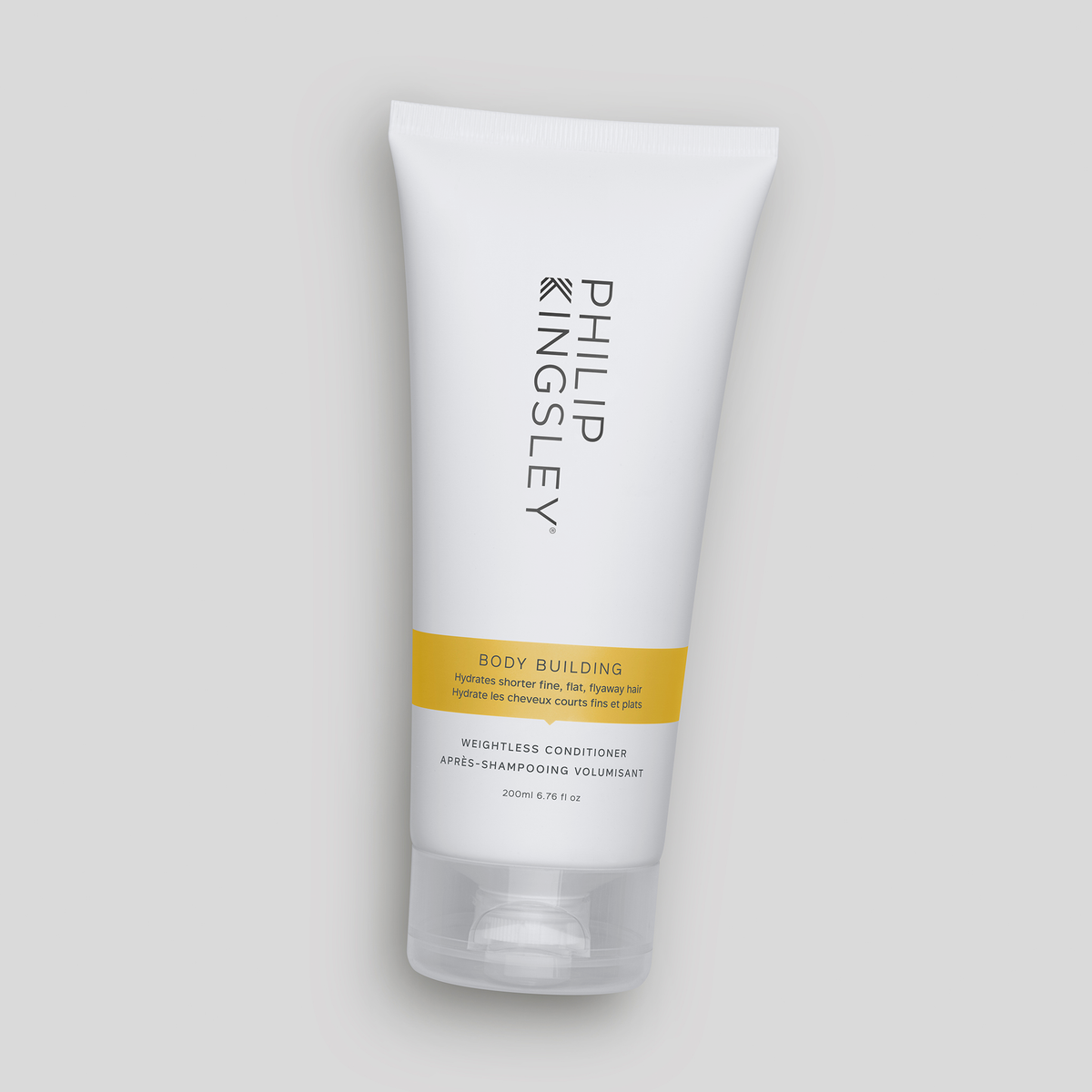 Auf einem hellgrauen Hintergrund steht eine weiße Tube „Philip Kingsley Body Building Conditioner“ mit einem gelben Etikett.