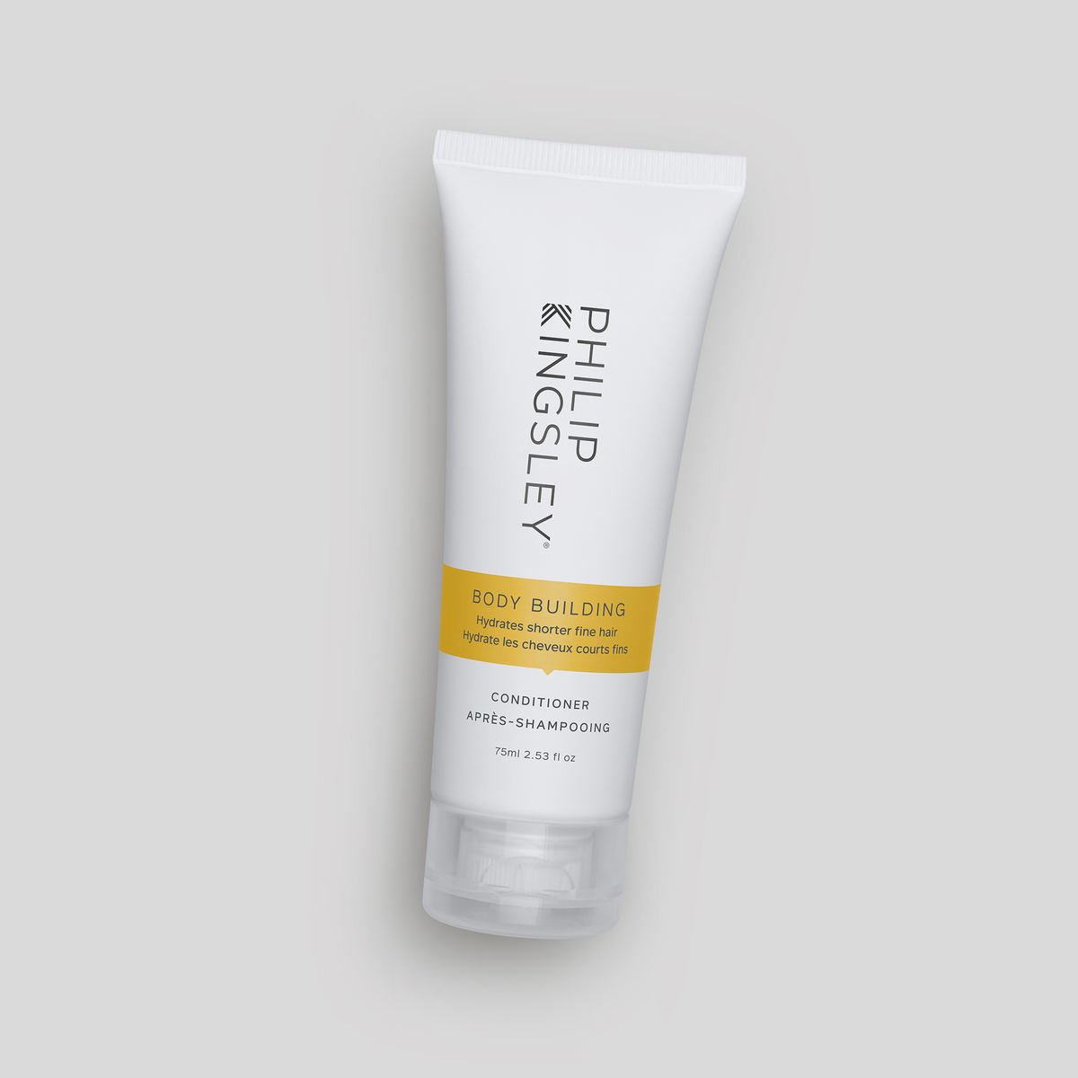 Eine weiße Tube „Philip Kingsley Body Building Conditioner“ steht vor einem hellgrauen Hintergrund.