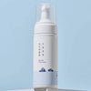 Schlichte weiße Flasche des Round Lab 1025 Dokdo Bubble Foam mit Pumpspender und blauem Insel-Design, vor hellblauem Hintergrund stilvoll in Szene gesetzt.