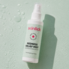 Eine Skinlick Redness Relief Mist-Sprühflasche auf einer nassen Oberfläche.