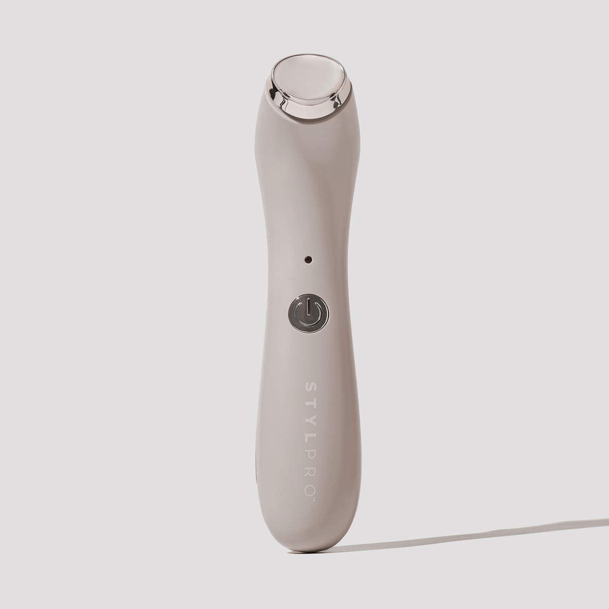 Beiger STYLPRO-Gesichtsmassager mit Kühlfunktion und silbernem Einschaltknopf, aufrecht auf hellem Hintergrund abgebildet.