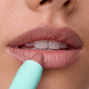 Eine Nahaufnahme von Lippen, auf die der Lippenstift „SWEED Le Lipstick“ in Nude-Pink aufgetragen wird; der Lippenstift kommt aus einer mintgrünen Hülse.