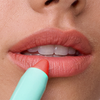 Eine Nahaufnahme der Lippen mit dem Lippenstift „Le Lipstick“ in der Farbe „Coral“ von SWEED, der aus einer hellgrünen Tube aufgetragen wurde.