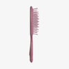 Eine UNbrush Detangling Hair Brush in Rosa mit fehlenden und gebogenen Borsten, aufrecht stehend auf weißem Hintergrund.