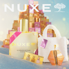 NUXE Holiday-Set mit Adventskalender, weißer Tasche, Geschenkboxen und Mini-Huile Prodigieuse Ölen, festlich inszeniert vor goldenem Hintergrund.