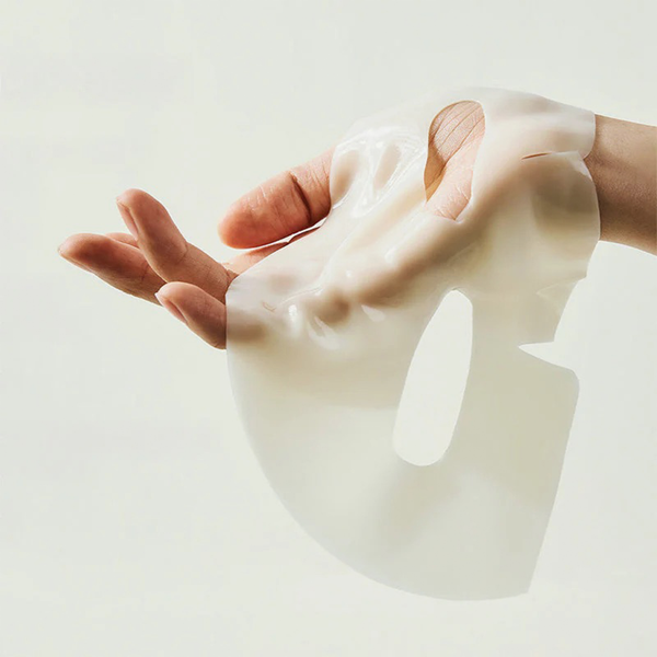 Eine Hand hält die Biodance Radiant Vita Niacinamide Real Deep Mask vor einem hellen Hintergrund.