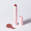 Ein rosa BLONDESISTER 2-IN-1-Stift „IT’S UP TO YOU – LIP OR CHEEK“ steht aufrecht und ohne Kappe neben einem bräunlichen Fleck auf weißem Hintergrund.