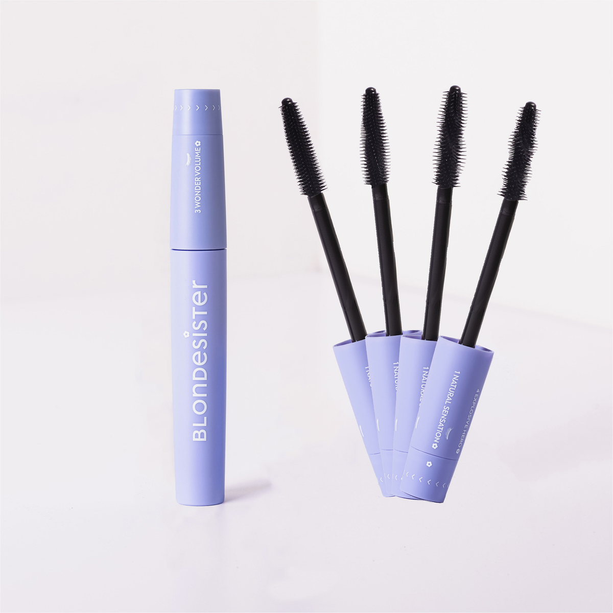 Fünf violette BLONDESISTER 4-IN-1-CLICK-&-TURN-MASCARA-Tuben, eine steht aufrecht, bei vier sind die schwarzen Applikatoren und Bürsten zu sehen.