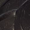 Nahaufnahme des BLONDESISTER GLOWEYE-LIDSCHATTENS: dunkles, schimmerndes Metallic-Finish mit strukturierten Rillen und funkelnden Akzenten.
