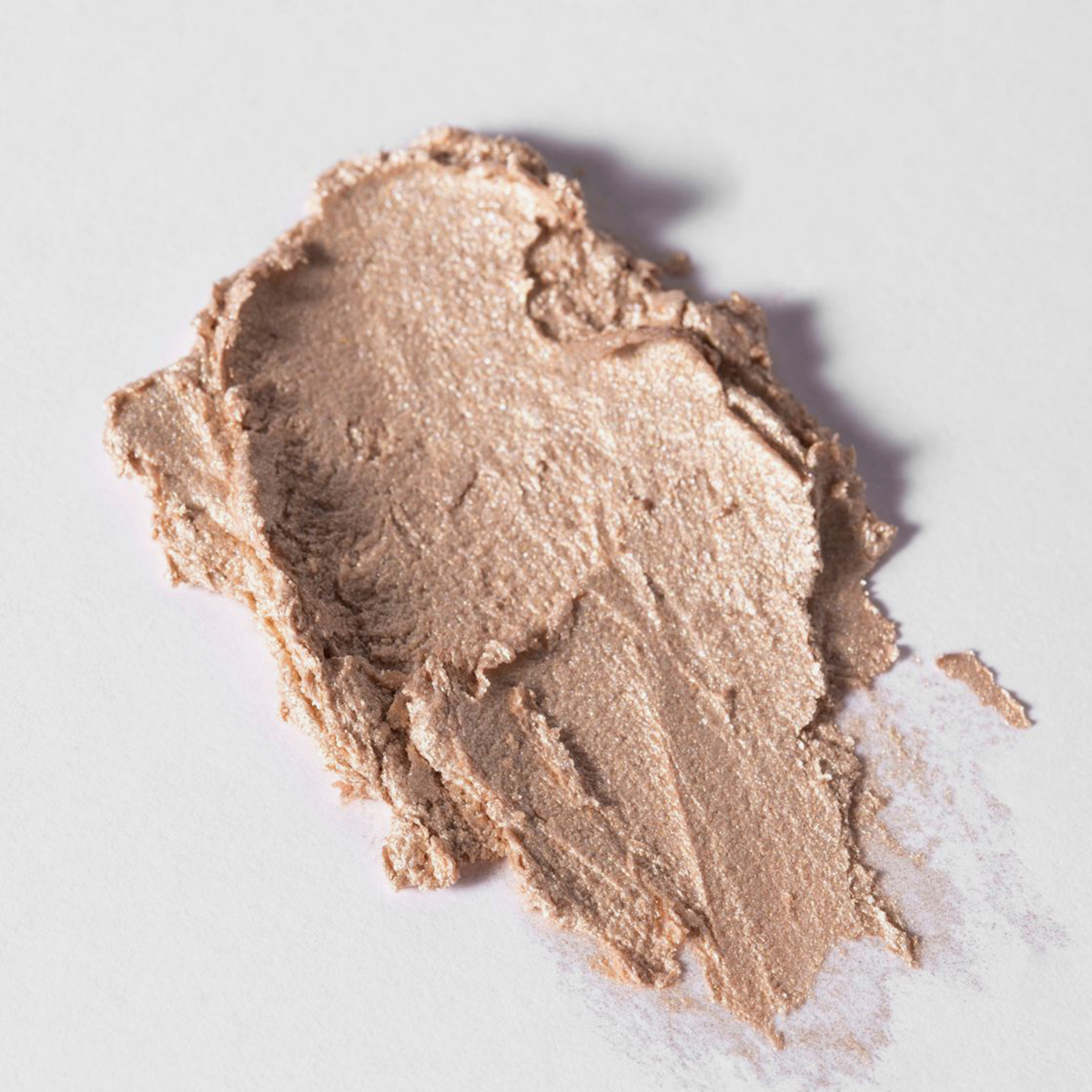 BLONDESISTER READY TO GLOW HIGHLIGHTER CRYSTAL MOOD 01: Eine schimmernde, beigefarbene Creme, aufgetragen auf einer weißen Oberfläche.