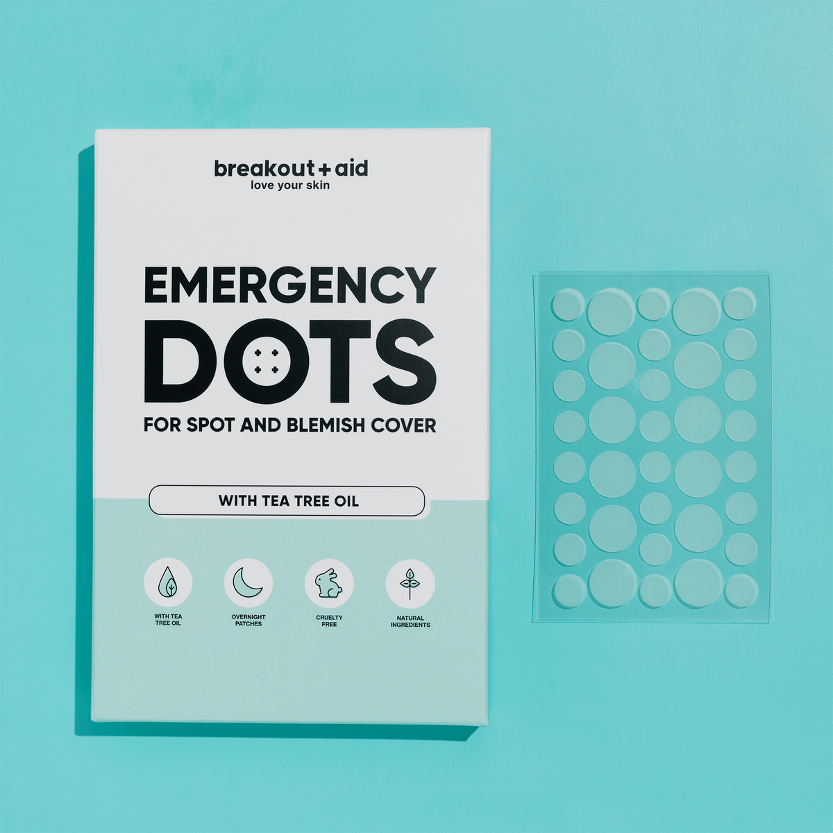 Eine Schachtel Emergency Dots mit Teebaumöl neben einer durchsichtigen Folie mit einzelnen runden Akne-Pflastern.