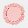 Ein kreisförmiger Haufen loser rosafarbener Bright & Blur Setting Powder von Catrice Cosmetics bildet eine glatte Mitte auf weißem Hintergrund.