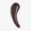 Ein geschwungener Strich mit dem „Beauty Glosswork 4D Ultra Shine Plumping Gloss“ von Danessa Myricks in glänzendem Dunkelbraun auf weißem Hintergrund.