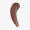 Ein Strich des „Glosswork 4D Ultra Shine Plumping Gloss“ von Danessa Myricks Beauty in der Farbe „Glossy Brown“ auf weißem Hintergrund.