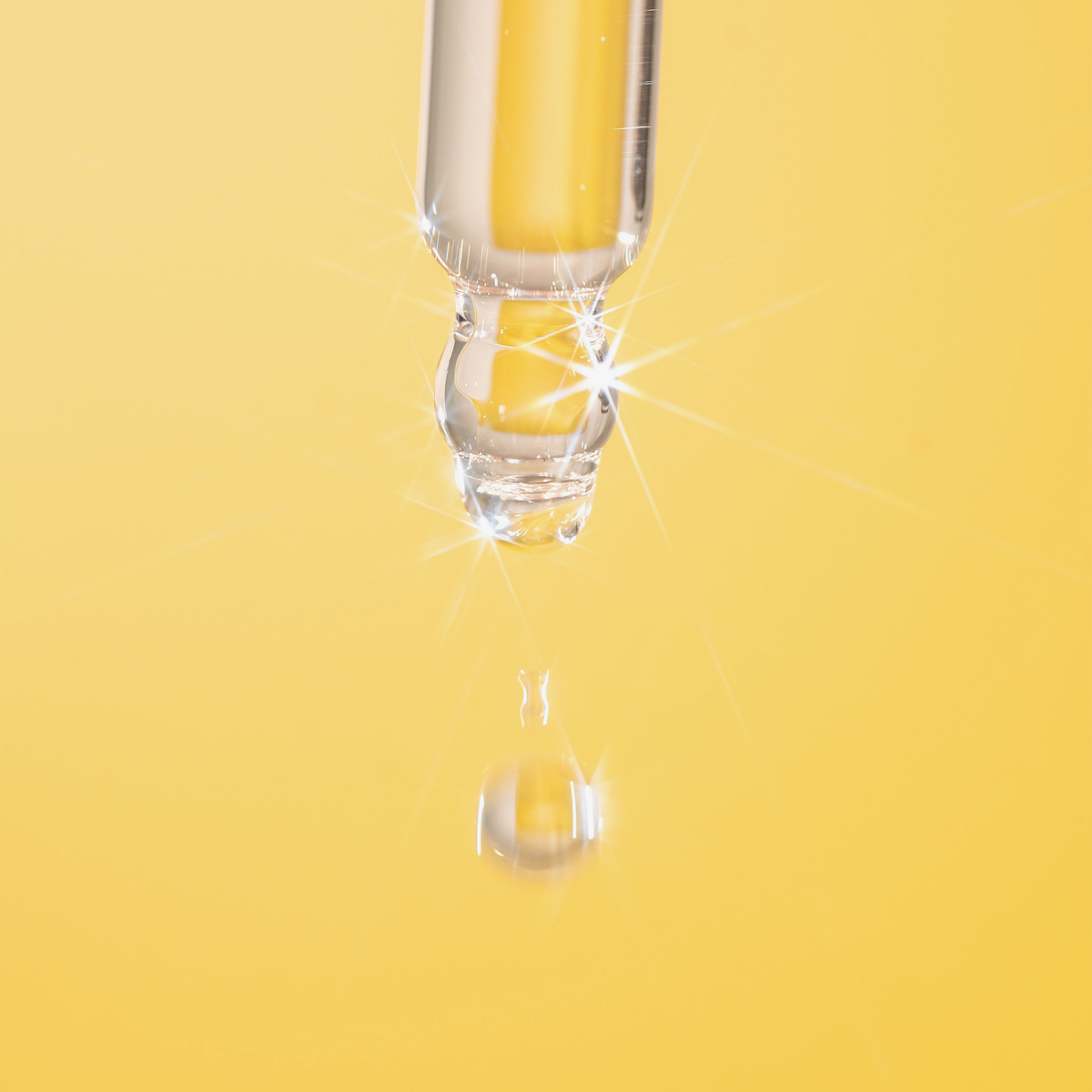 Ein glänzender Glastropfer von Hair Syrup's Honeydew setzt einen Tropfen vor einem leuchtend gelben Hintergrund frei.