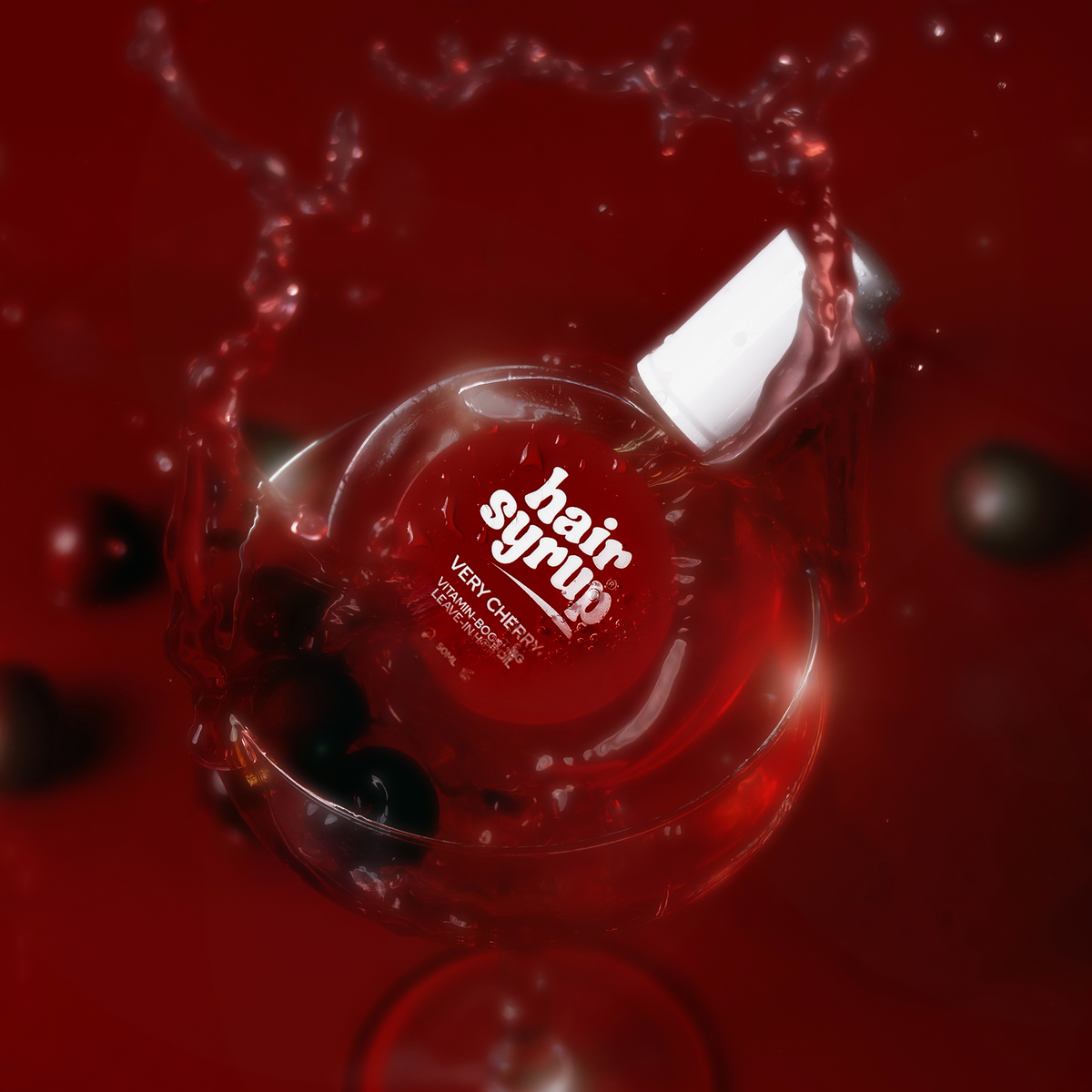 Eine Flasche Very Cherry von Hair Syrup plätschert in ein Weinglas, das mit Flüssigkeit und dunklen Kirschen gefüllt ist.