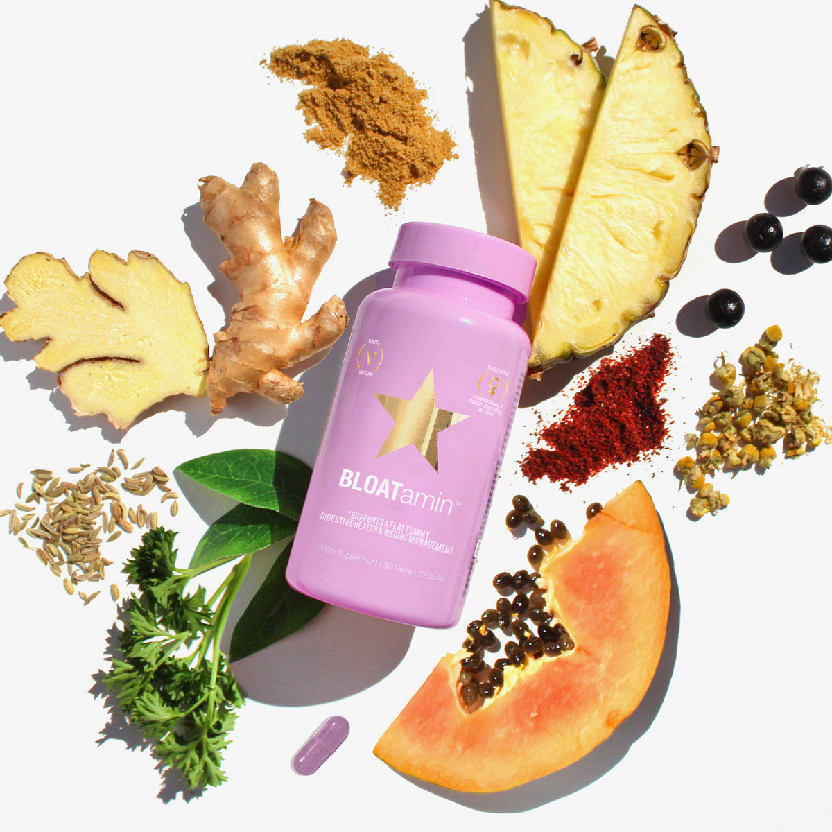Violette BLOATamin-Flasche, umgeben von Ingwer, Ananas, Papaya, Kräutern und Gewürzen.