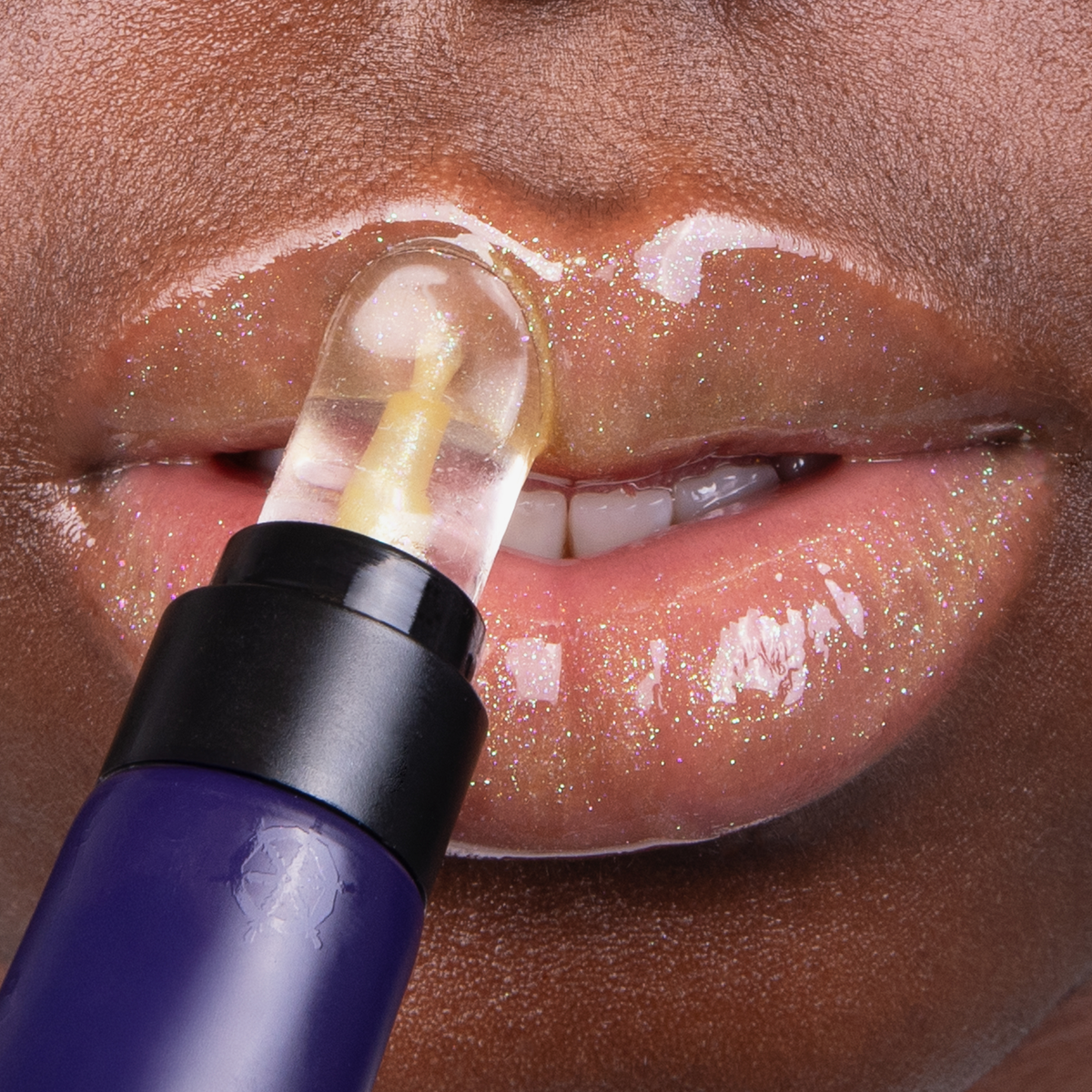 Eine Nahaufnahme von glänzenden Lippen, während der goldgelbe The SpongeBob Movie Lip Gloss 'SpongeBob' von Lethal Cosmetics aufgetragen wird.