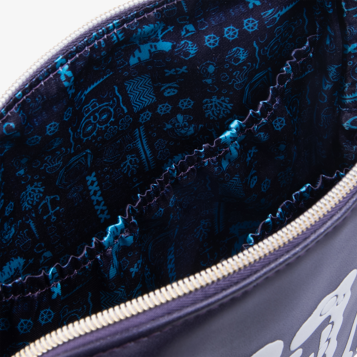 Nahaufnahme des Innenfutters der The SpongeBob Movie Skull & Bones Makeup Bag von Lethal Cosmetics mit blau gemustertem Design und zwei Innentaschen.